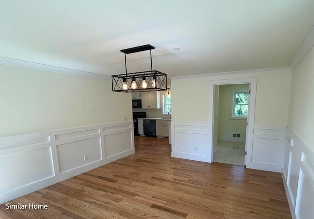 unfurnished dining area featuring hardwood / wood-style floors and ornamental molding