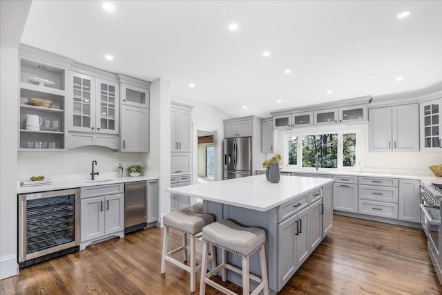 kitchen featuring appliances with stainless steel finishes, beverage cooler, sink, a center island, and dark hardwood / wood-style floors