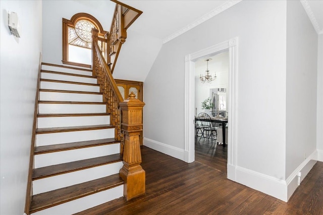 staircase featuring hardwood / wood-style flooring, crown molding, and a chandelier