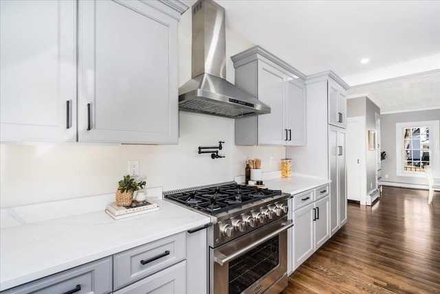 kitchen with high end stainless steel range oven, wall chimney range hood, light stone counters, dark hardwood / wood-style floors, and ornamental molding