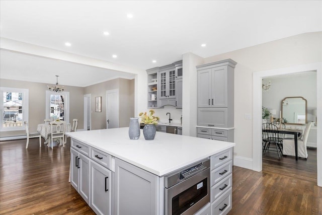 kitchen featuring gray cabinetry, dark hardwood / wood-style flooring, a kitchen island, and a notable chandelier