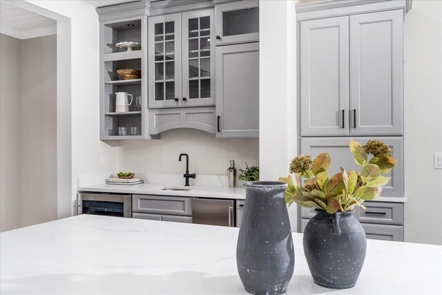 bar with light stone countertops, wine cooler, gray cabinets, and stainless steel dishwasher