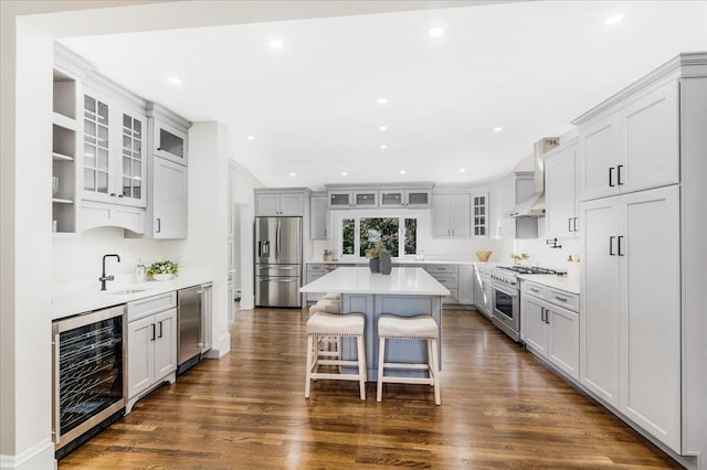 kitchen featuring a center island, beverage cooler, a kitchen breakfast bar, dark hardwood / wood-style floors, and appliances with stainless steel finishes