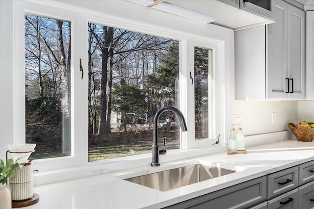 interior space featuring gray cabinets, light stone countertops, and sink