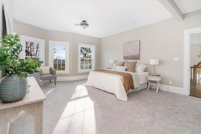 bedroom with beam ceiling and light colored carpet