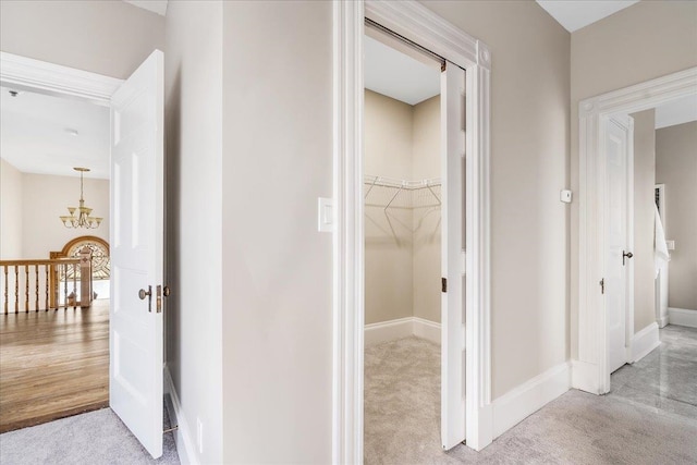 hallway featuring light carpet and a chandelier