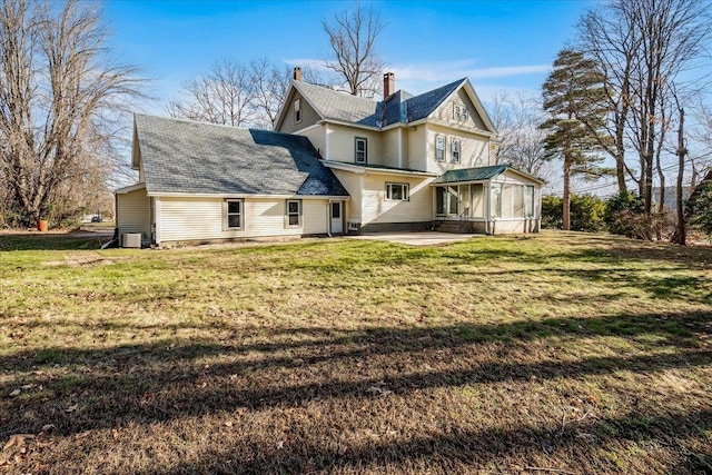 back of property with a sunroom, a patio area, and a yard