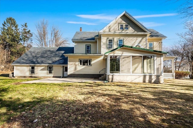 back of house with a sunroom, a patio, and a lawn