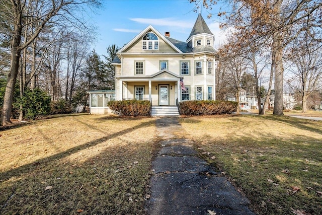 victorian house with a porch, a front lawn, and a sunroom