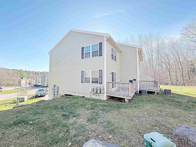 back of property with a deck, a yard, and central AC