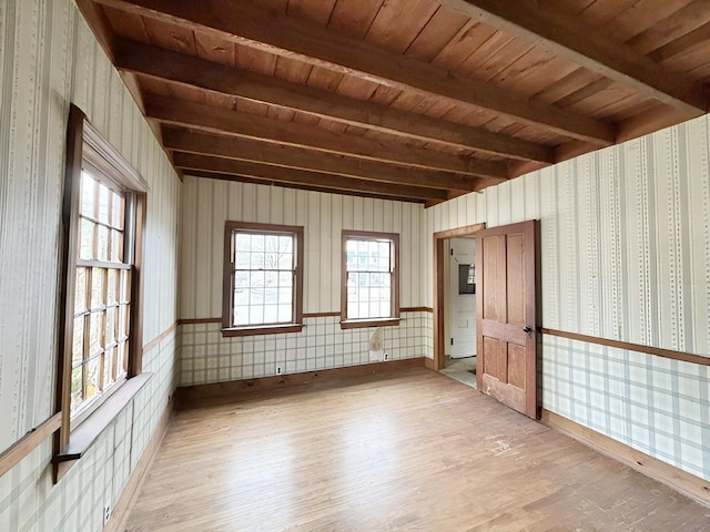 spare room featuring beam ceiling, light wood-type flooring, and wooden ceiling