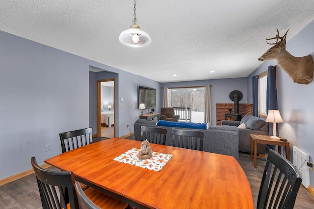 dining area with a wood stove, hardwood / wood-style floors, and a textured ceiling