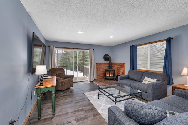 living room with a wood stove, wood-type flooring, and a textured ceiling