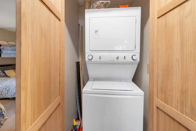 laundry room featuring carpet and stacked washer / drying machine