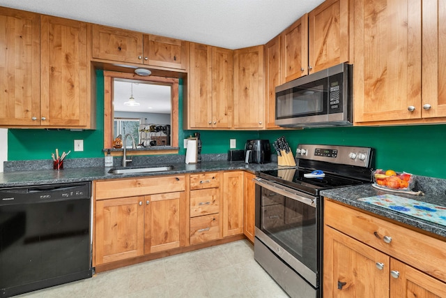 kitchen featuring a textured ceiling, dark stone countertops, sink, and appliances with stainless steel finishes