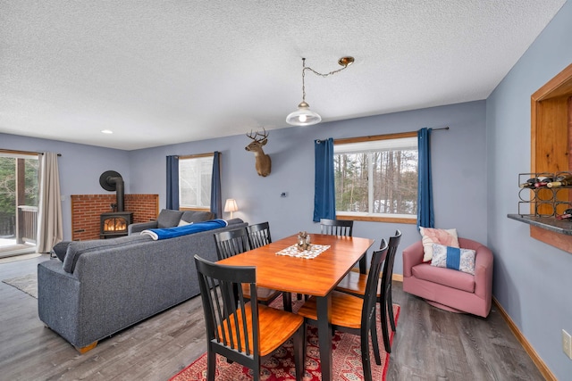 dining room featuring hardwood / wood-style floors, a wood stove, and a textured ceiling