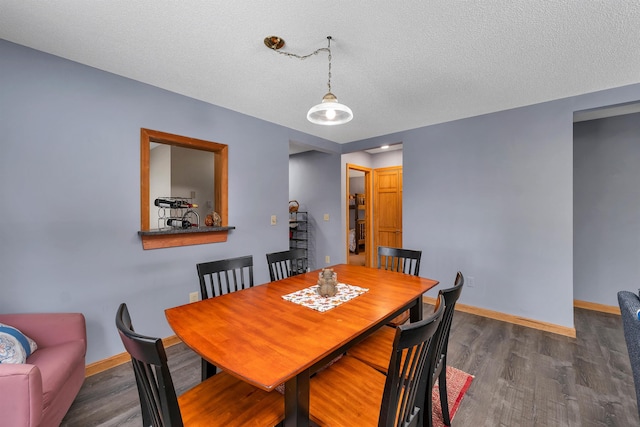 dining space with dark hardwood / wood-style floors and a textured ceiling