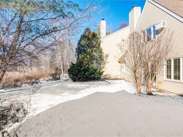 snowy yard featuring a wall unit AC