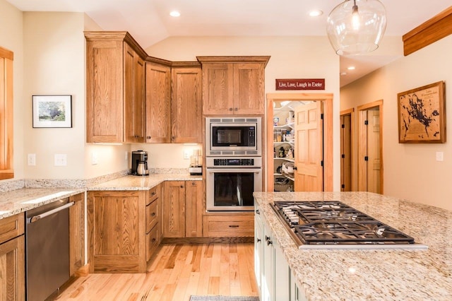 kitchen featuring decorative light fixtures, stainless steel appliances, light stone counters, and light hardwood / wood-style floors