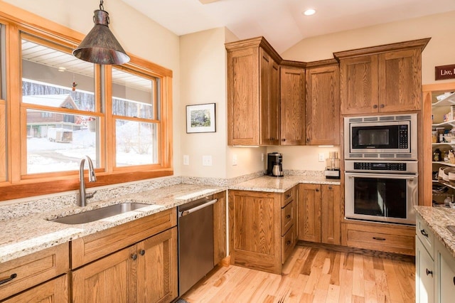 kitchen featuring sink, hanging light fixtures, light hardwood / wood-style flooring, vaulted ceiling, and stainless steel appliances