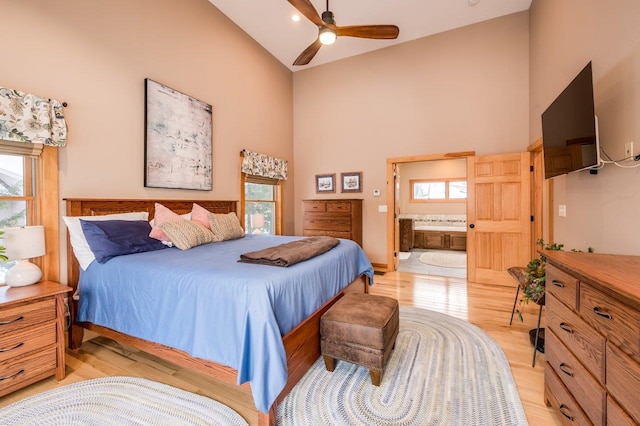 bedroom featuring ensuite bathroom, ceiling fan, light wood-type flooring, and high vaulted ceiling