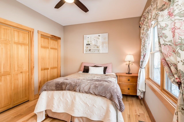 bedroom featuring light hardwood / wood-style flooring, ceiling fan, and multiple closets