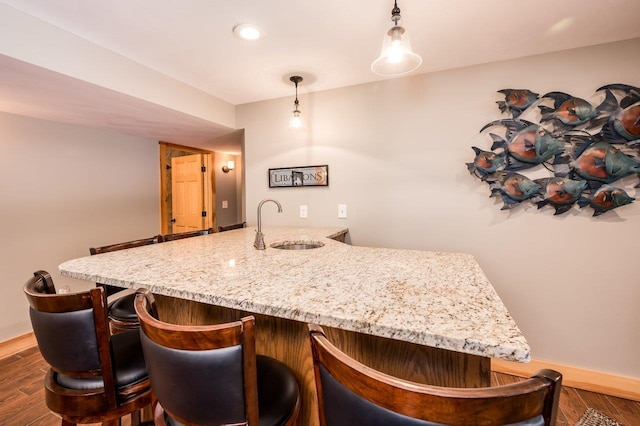 bar featuring sink, pendant lighting, and dark hardwood / wood-style floors