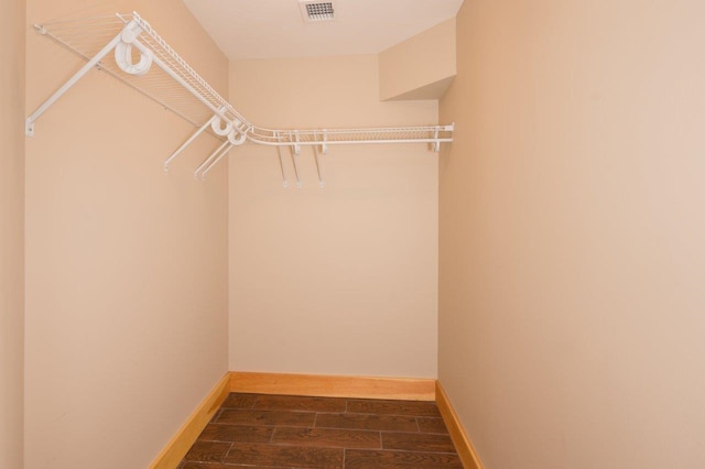 walk in closet with dark hardwood / wood-style floors