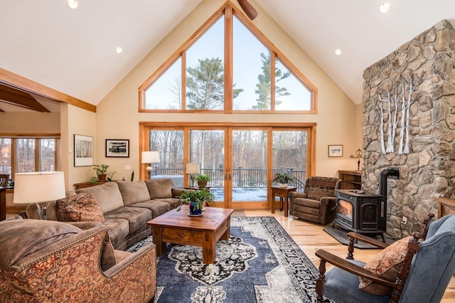 living room featuring a wealth of natural light, a wood stove, high vaulted ceiling, and light hardwood / wood-style flooring