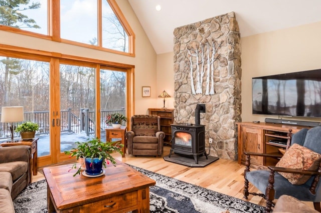 living room featuring hardwood / wood-style floors, a wood stove, high vaulted ceiling, and french doors