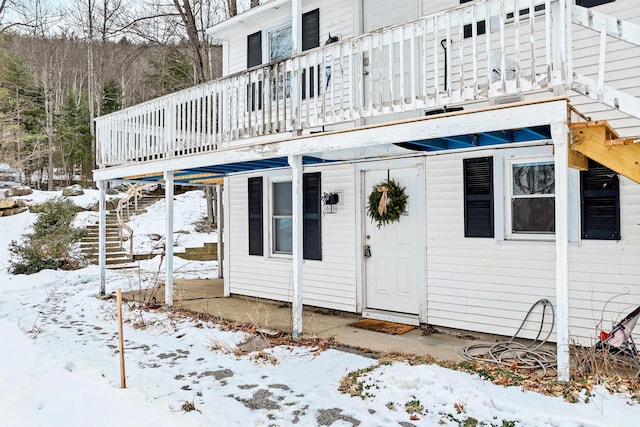 snow covered property entrance with a wooden deck