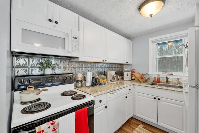 kitchen with white appliances, a textured ceiling, white cabinetry, sink, and backsplash