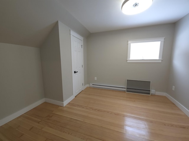 additional living space with light hardwood / wood-style floors and a baseboard heating unit