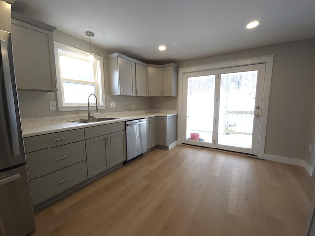 kitchen with appliances with stainless steel finishes, hanging light fixtures, gray cabinetry, and sink