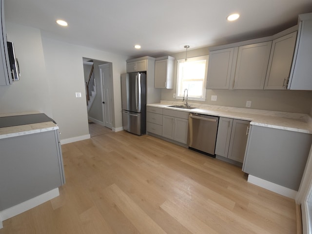 kitchen featuring gray cabinetry, sink, stainless steel appliances, light hardwood / wood-style flooring, and decorative light fixtures