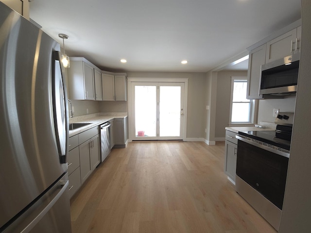 kitchen with pendant lighting, plenty of natural light, light hardwood / wood-style floors, and stainless steel appliances