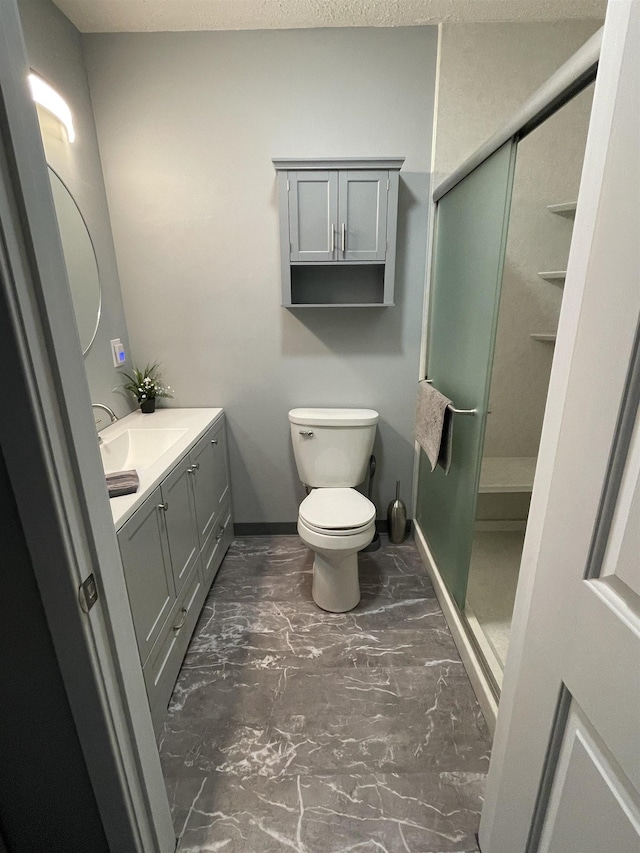 bathroom featuring vanity, toilet, and a shower with door