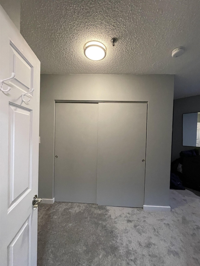 interior space with carpet flooring, a closet, and a textured ceiling