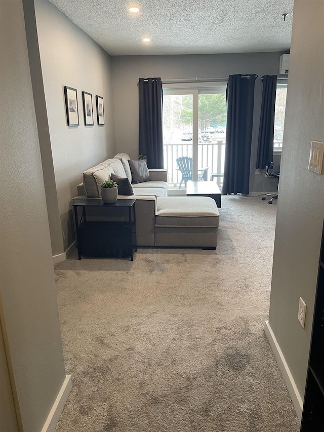 carpeted living room with a wall mounted air conditioner and a textured ceiling