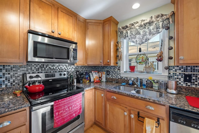 kitchen featuring decorative backsplash, stainless steel appliances, dark stone countertops, and sink