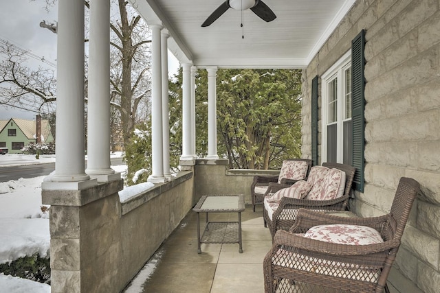 snow covered patio with ceiling fan and a porch