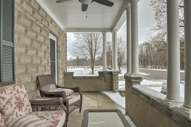 snow covered patio featuring ceiling fan and a porch