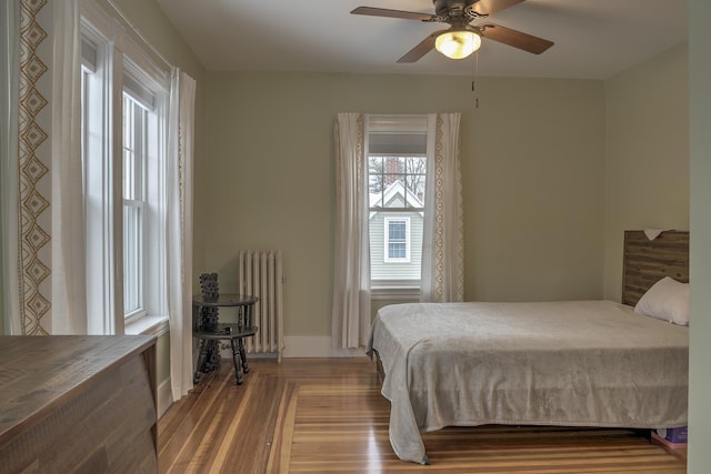 bedroom with ceiling fan, radiator heating unit, and light hardwood / wood-style floors