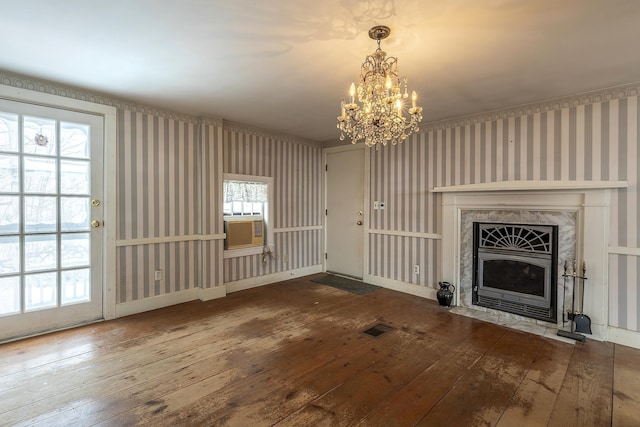 unfurnished living room with hardwood / wood-style floors, a notable chandelier, and a fireplace