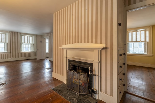 unfurnished living room featuring plenty of natural light and dark hardwood / wood-style floors