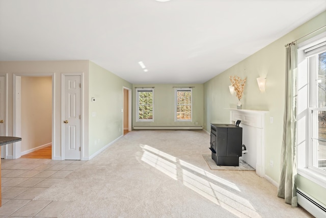 tiled living room featuring a wood stove, baseboard heating, and a wealth of natural light