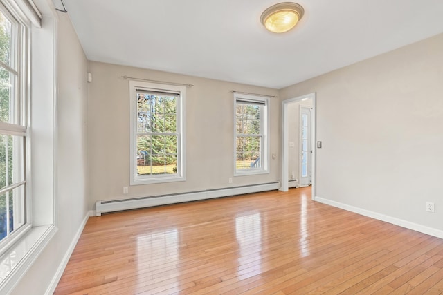 spare room featuring baseboard heating and light hardwood / wood-style flooring