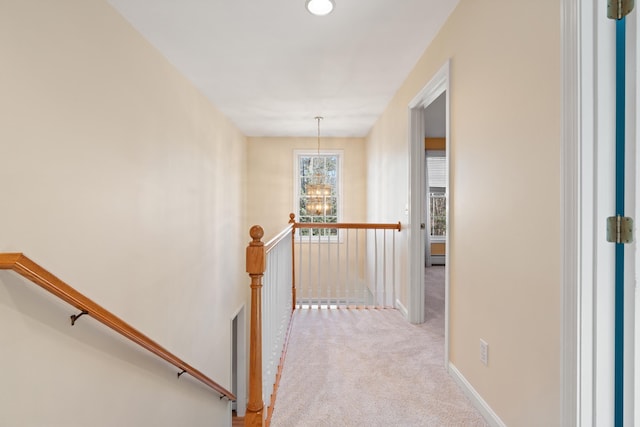 corridor featuring light carpet and a notable chandelier