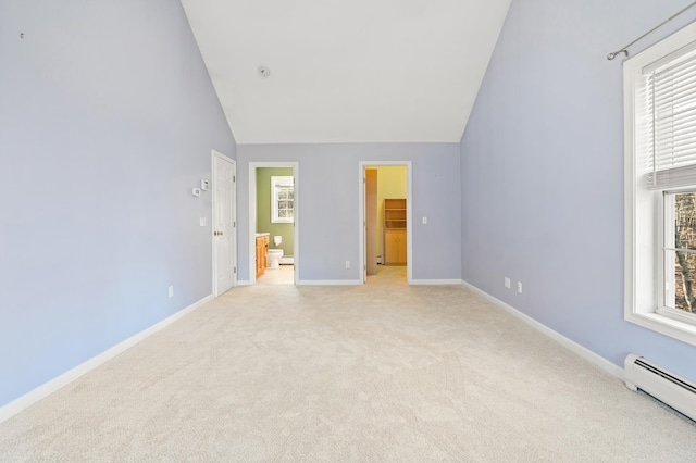 unfurnished bedroom with multiple windows, a spacious closet, light carpet, and a baseboard heating unit