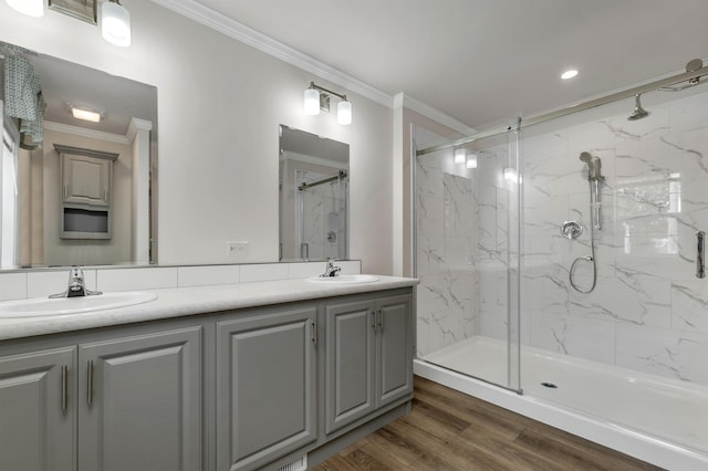 bathroom with hardwood / wood-style flooring, vanity, crown molding, and walk in shower